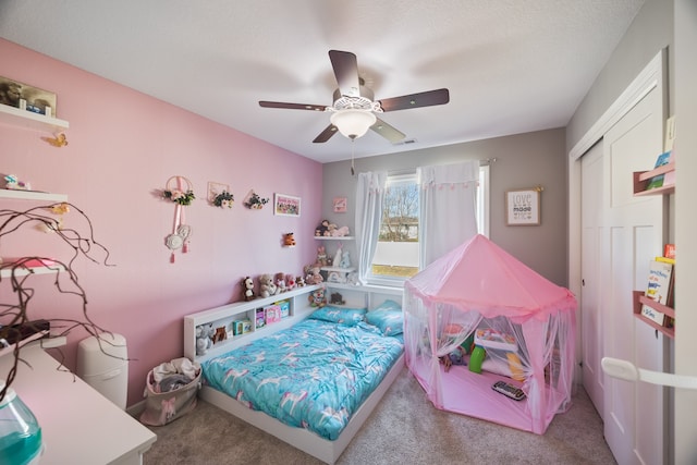 bedroom with ceiling fan, a closet, light colored carpet, and a textured ceiling