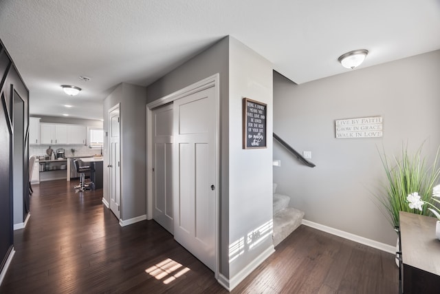 corridor featuring dark wood-type flooring and a textured ceiling