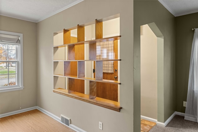 unfurnished room featuring wood-type flooring, a textured ceiling, and ornamental molding