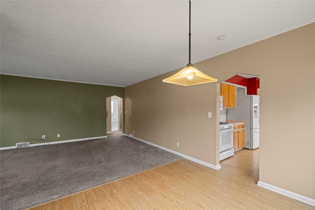 empty room featuring crown molding, a textured ceiling, and light wood-type flooring