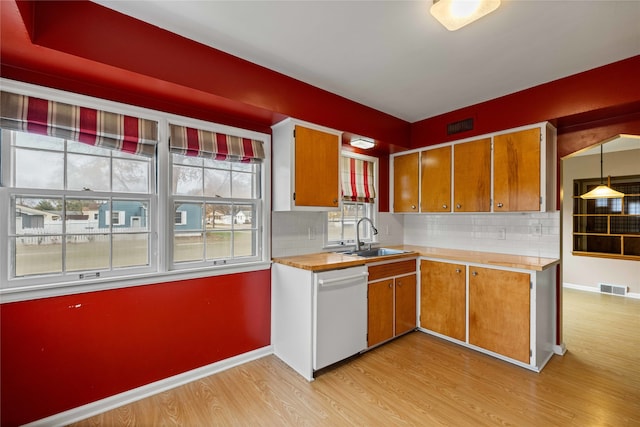 kitchen with decorative backsplash, sink, decorative light fixtures, light hardwood / wood-style flooring, and dishwasher