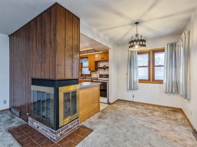 kitchen with white electric range oven, dark carpet, sink, and wooden walls