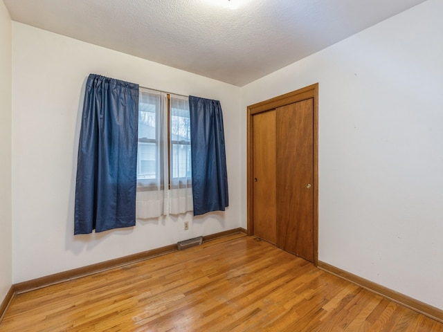 empty room featuring wood-type flooring and a textured ceiling