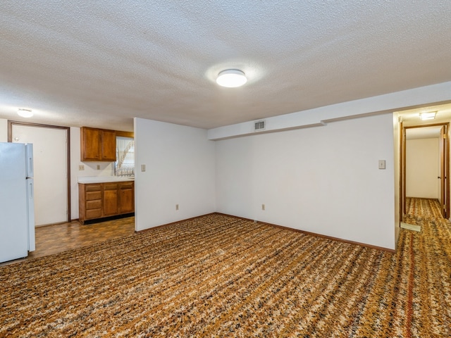 unfurnished living room with dark carpet and a textured ceiling