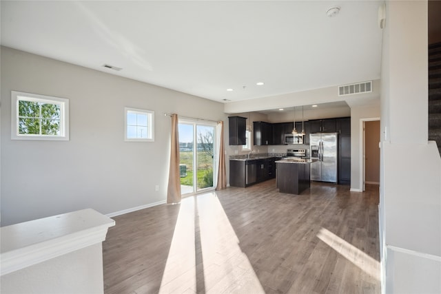 kitchen featuring decorative light fixtures, a center island, dark hardwood / wood-style flooring, and appliances with stainless steel finishes