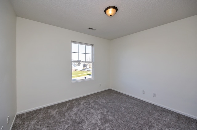 empty room with dark carpet and a textured ceiling