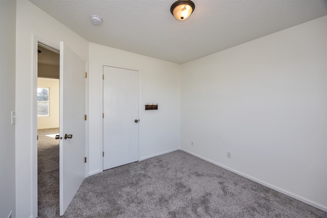 spare room featuring a textured ceiling and carpet floors