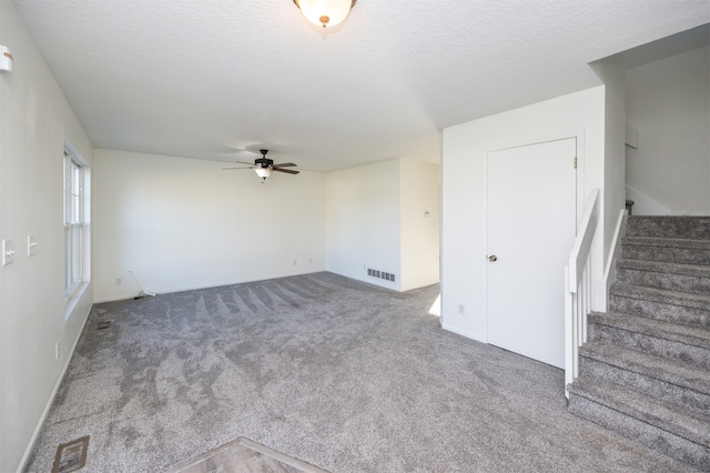 interior space featuring ceiling fan, carpet, and a textured ceiling