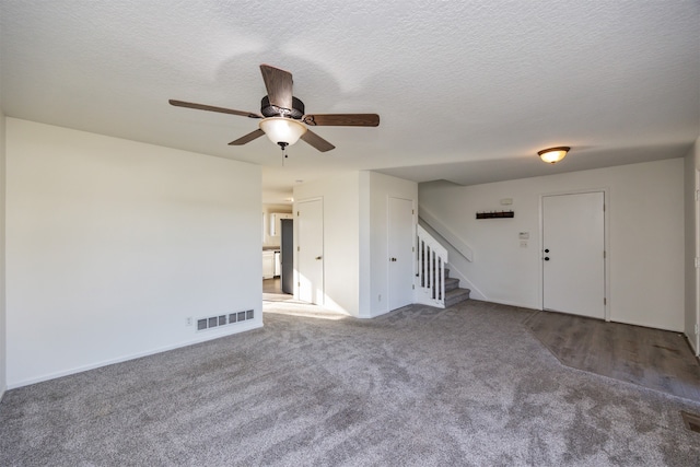 unfurnished room with a textured ceiling, carpet floors, and ceiling fan