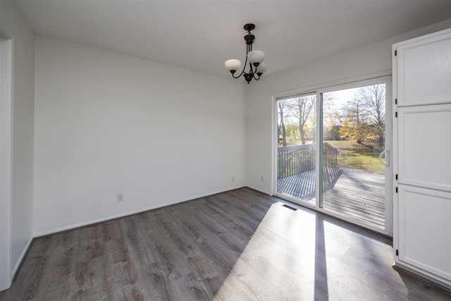 unfurnished dining area with an inviting chandelier and dark wood-type flooring