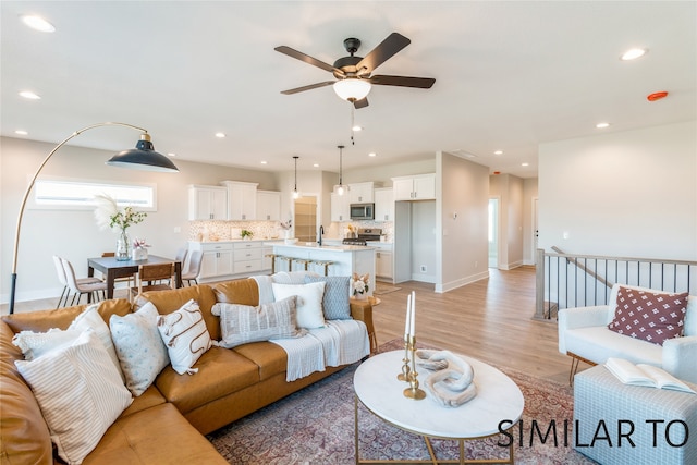 living room with light hardwood / wood-style flooring, ceiling fan, and sink