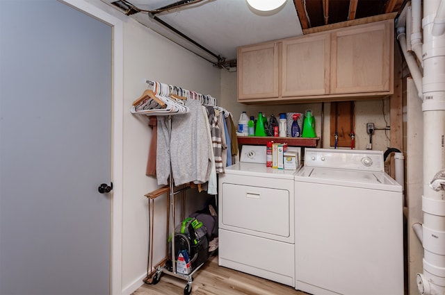 laundry room featuring cabinets, light hardwood / wood-style flooring, and washer and clothes dryer