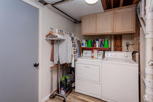 laundry area with cabinet space, light wood-style floors, and washing machine and clothes dryer