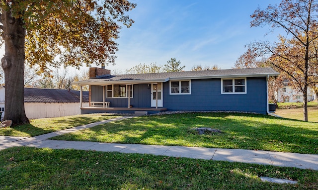 ranch-style home featuring cooling unit, covered porch, and a front yard