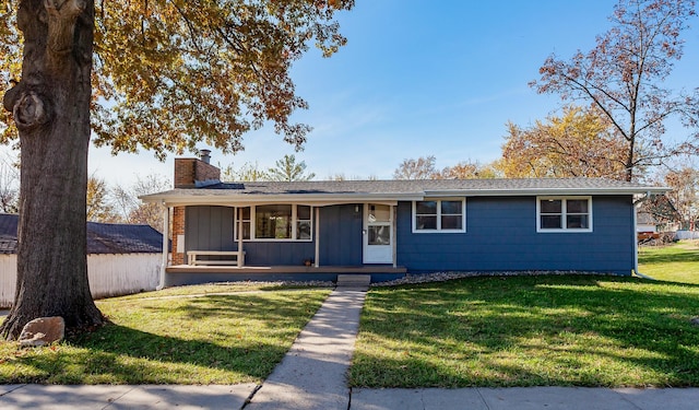 ranch-style house featuring a porch, board and batten siding, a chimney, and a front lawn