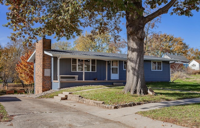 single story home featuring a chimney, a front lawn, a porch, and board and batten siding