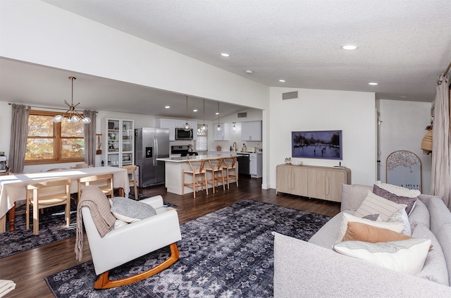 living room with a notable chandelier, dark hardwood / wood-style floors, sink, and a textured ceiling