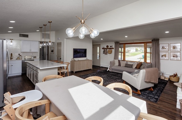 dining room with sink, lofted ceiling, dark wood-type flooring, and a chandelier