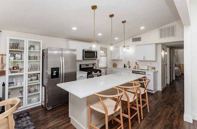 kitchen featuring white cabinets, dark hardwood / wood-style floors, stainless steel appliances, and hanging light fixtures