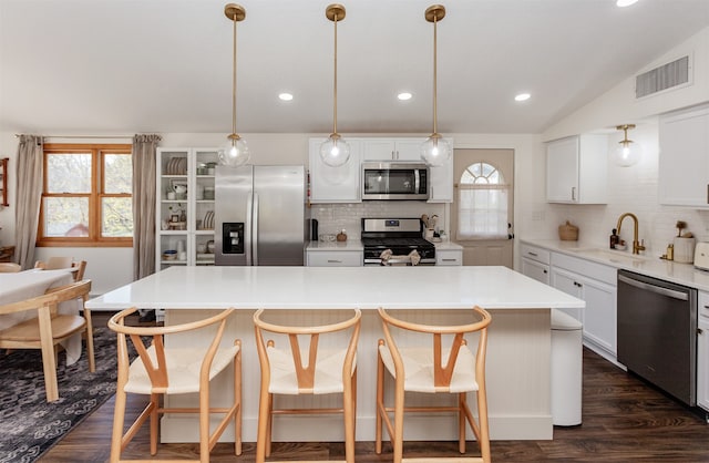 kitchen with appliances with stainless steel finishes, tasteful backsplash, sink, a kitchen island, and lofted ceiling