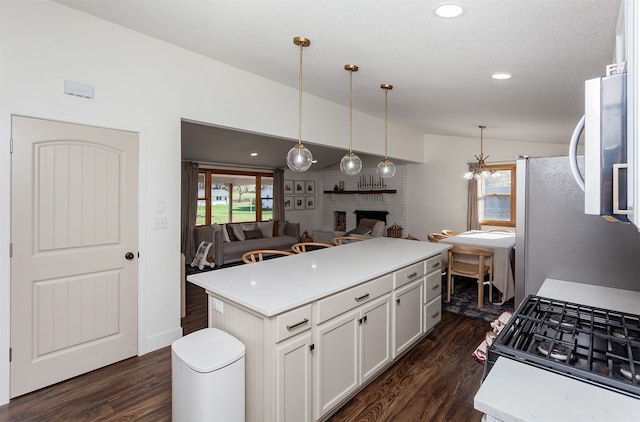 kitchen featuring dark hardwood / wood-style flooring, a kitchen island, vaulted ceiling, and a brick fireplace