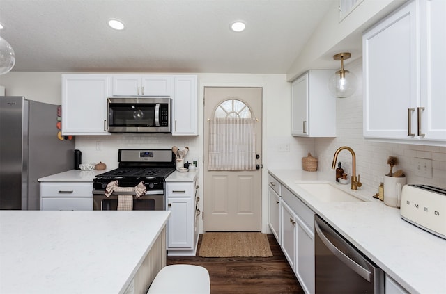 kitchen featuring white cabinetry, sink, decorative light fixtures, and appliances with stainless steel finishes