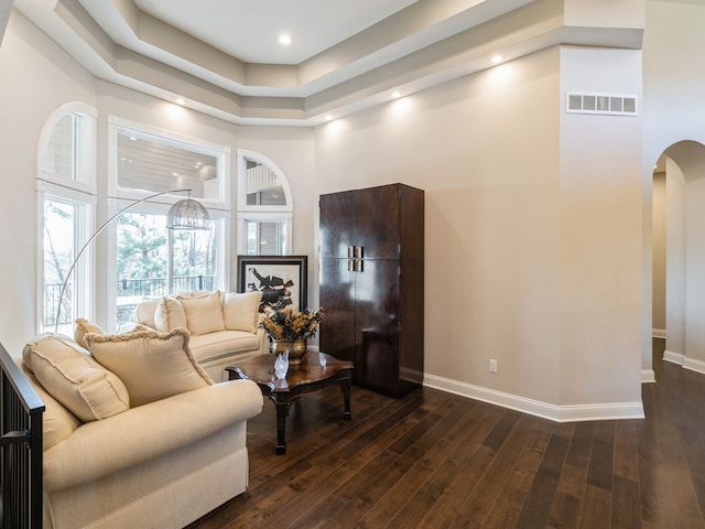 living room with a towering ceiling and dark wood-type flooring