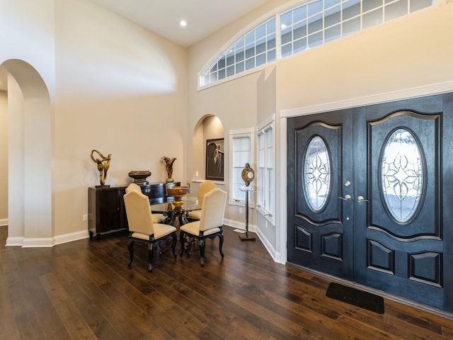 foyer featuring french doors, a towering ceiling, and dark wood-type flooring