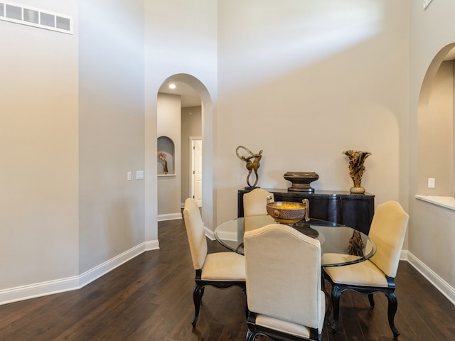 dining room with a towering ceiling and dark hardwood / wood-style floors