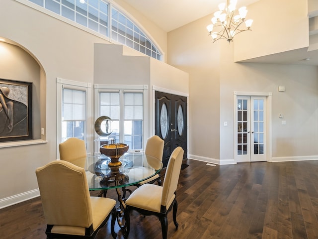 dining space featuring a chandelier, french doors, a towering ceiling, and dark hardwood / wood-style floors