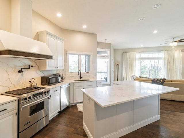 kitchen featuring a wealth of natural light, white cabinets, range hood, and appliances with stainless steel finishes