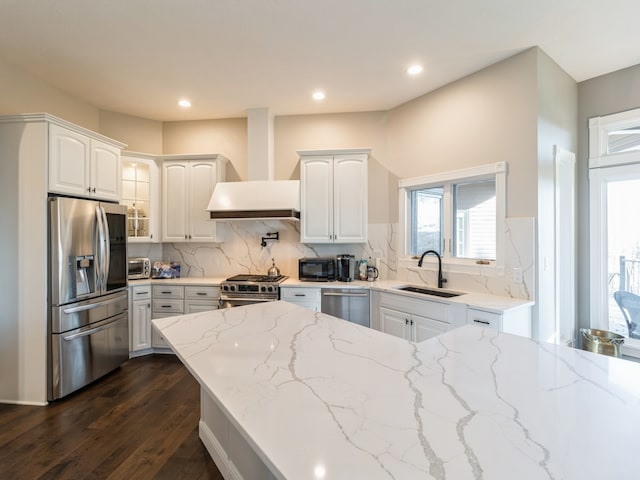 kitchen with light stone countertops, stainless steel appliances, white cabinetry, and sink