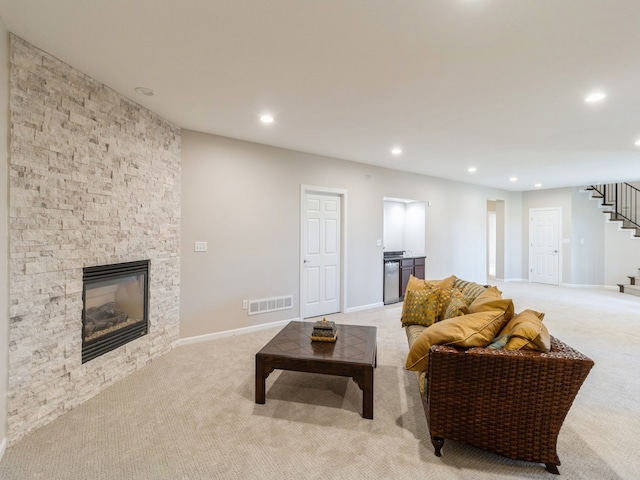 living room featuring a stone fireplace and light carpet