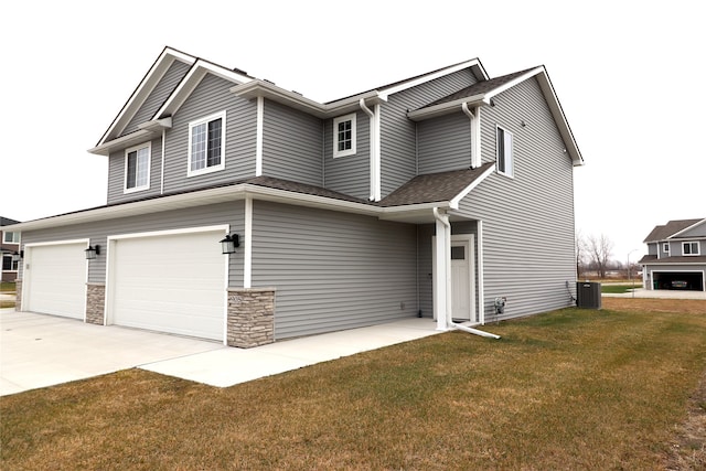 view of front facade with cooling unit, a garage, and a front lawn