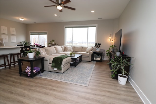 living room with light hardwood / wood-style flooring and ceiling fan