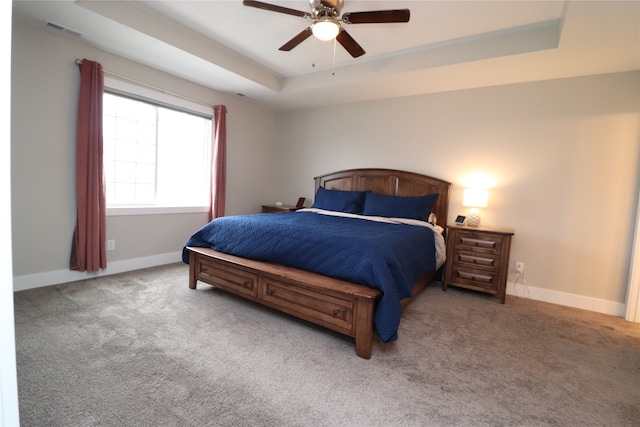 carpeted bedroom with a tray ceiling and ceiling fan