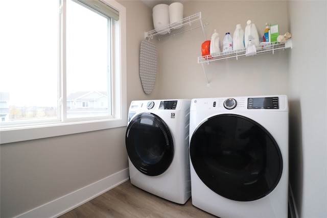 clothes washing area with washer and dryer, hardwood / wood-style floors, and plenty of natural light