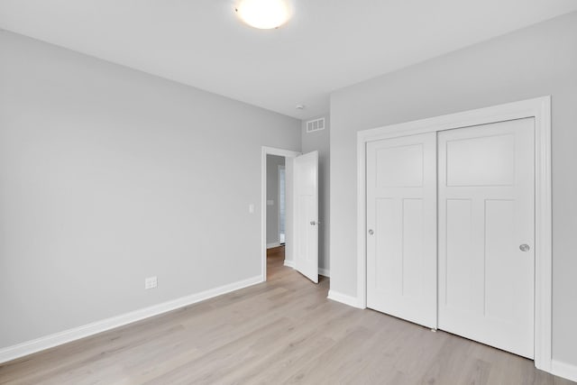 unfurnished bedroom with light wood-style floors, baseboards, visible vents, and a closet