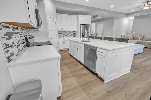 kitchen with light wood-style floors, appliances with stainless steel finishes, open floor plan, and a sink