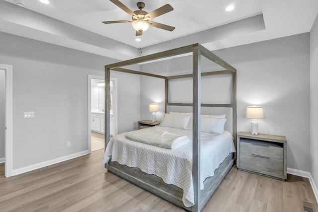 bedroom featuring light wood-style floors, baseboards, visible vents, and connected bathroom