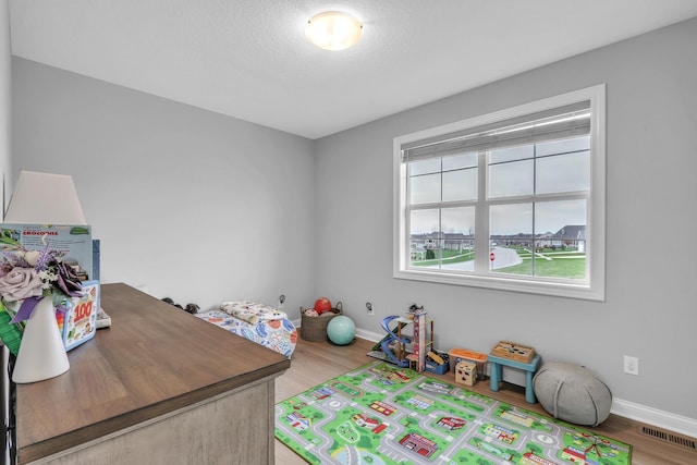 game room featuring a textured ceiling, wood finished floors, visible vents, and baseboards