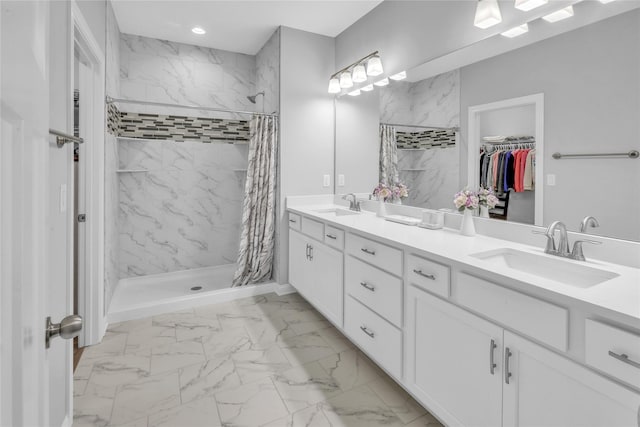 bathroom featuring double vanity, marble finish floor, a shower stall, and a sink