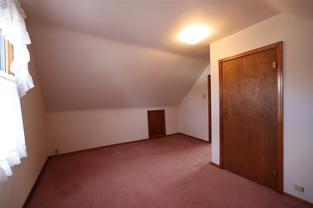 additional living space featuring light colored carpet and lofted ceiling