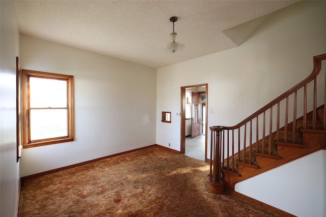 foyer entrance with carpet floors and a textured ceiling