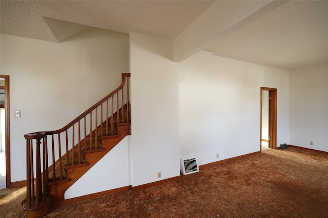 unfurnished room featuring carpet, beam ceiling, and a textured ceiling