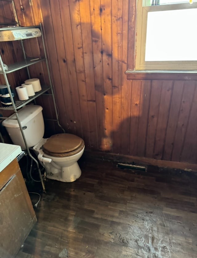 bathroom featuring hardwood / wood-style flooring, toilet, and wooden walls