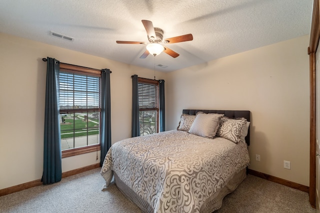 bedroom featuring ceiling fan, light carpet, and a textured ceiling