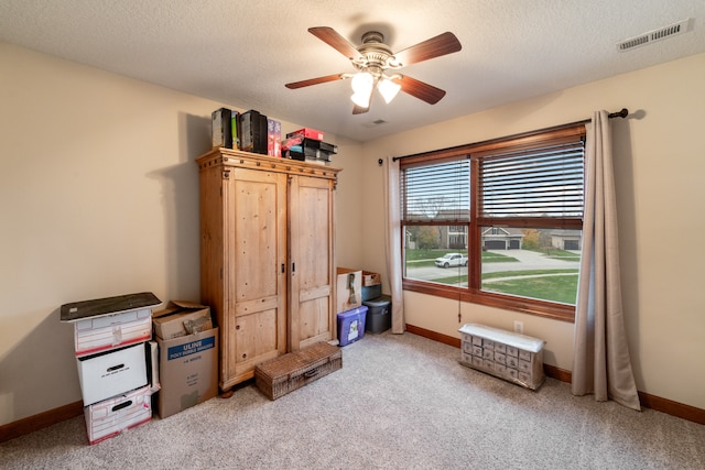 interior space featuring ceiling fan, light colored carpet, and a textured ceiling