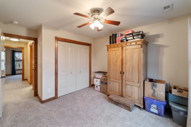 carpeted bedroom featuring ceiling fan, a textured ceiling, and a closet