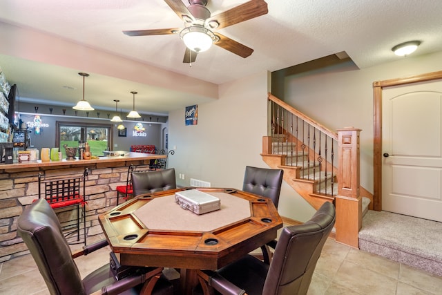 tiled office featuring bar area, a textured ceiling, and ceiling fan